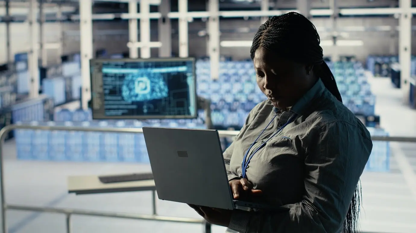 Администратор дата-центра проверяет дашборд ИИ с помощью ноутбука во время проверки систем ригов.